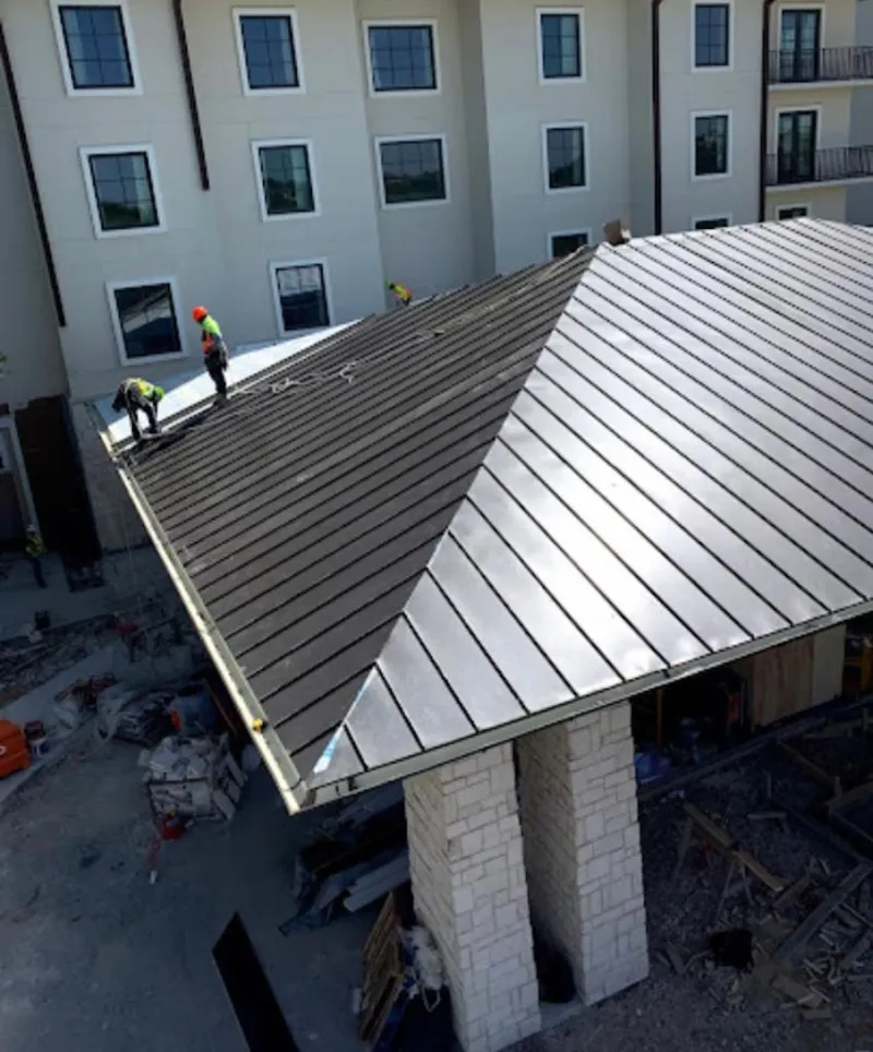 Crew installing standing seam metal roof panels on a commercial project in La Vista